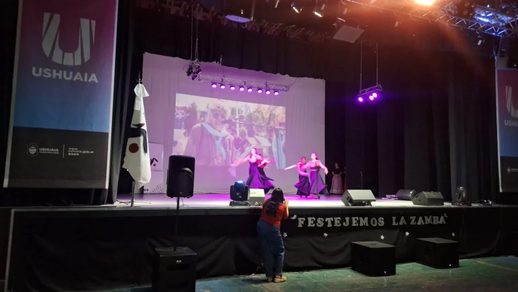Festejemos la Zamba: una tradición que nos une cada año Bailarinas con vestidos rojos y coloridos en escenario de Festejemos la Zamba, Ushuaia